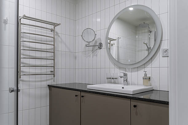 istock bathroom design with white tiles, white sink, gray bedside table under the sink, large and small round mirrors, hairdryer. 2212693887