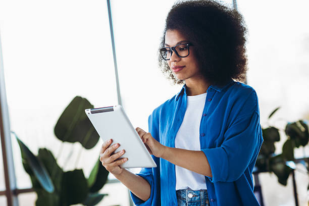 istock Young professional woman using a tablet in a modern office interior while reviewing work content 2212695140