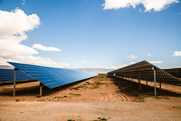 istock Symmetrical perspective of solar panel arrays on dry terrain under bright sky 2212695169