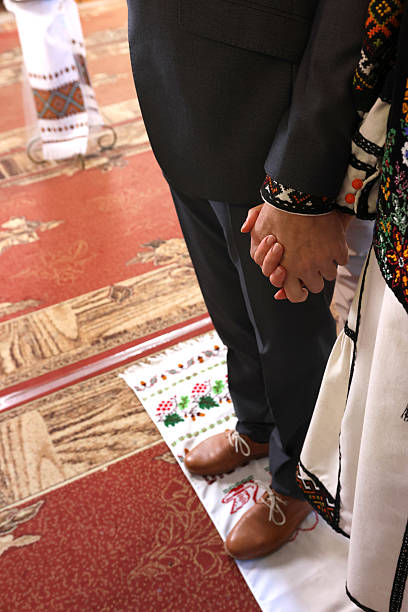 istock Newlyweds hold hands during a church wedding. 2212695398