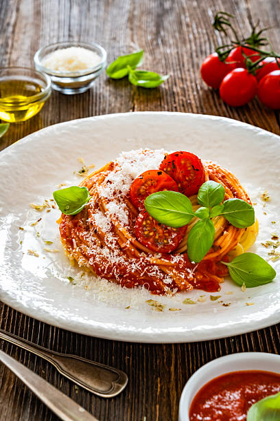 Spaghetti with tomato sauce and parmesan cheese served on wooden table
