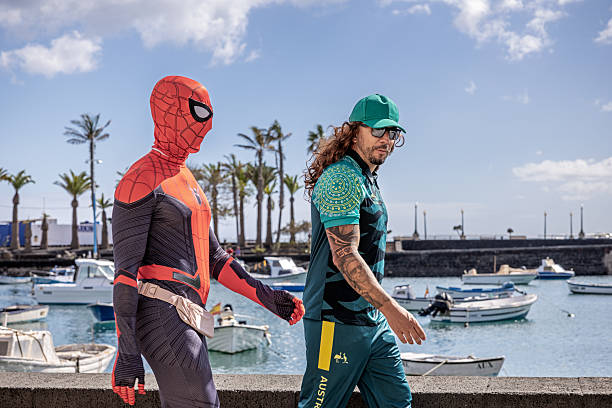 Arrecife, Lanzarote, Canary Islands, Spain - March 1st 2025:  A festive couple strolls along the waterfront in Arrecife, dressed in eye-catching carnival costumes. One is clad in a striking Spider-Man outfit, while the other sports a vibrant green and yellow ensemble with \
