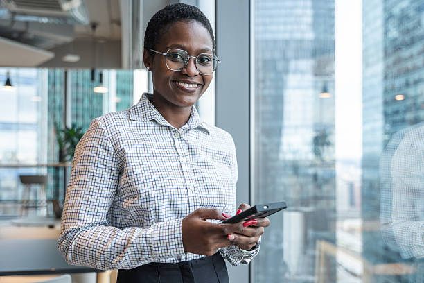 istock Smiling Professional Holding Smartphone in Modern Business Office Setting 2212701234