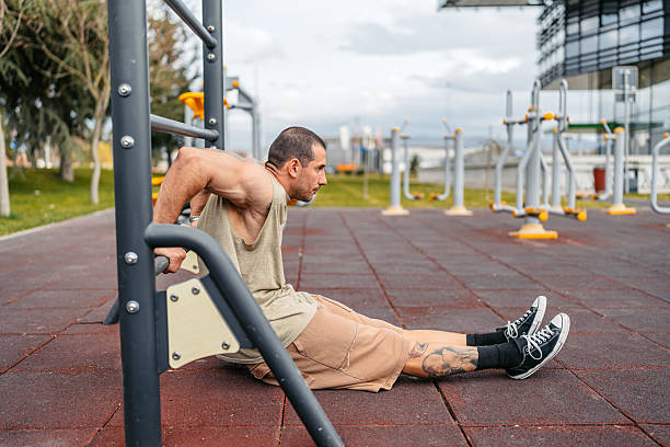 istock Young Man Doing Dips On A Bar In An Outdoor Gym 2212701254