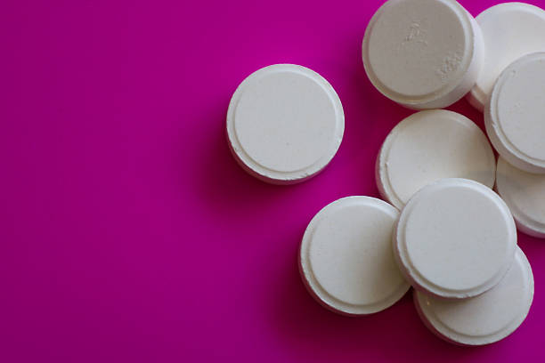 istock White round tablets are scattered on a bright pink surface. One tablet lies separately on the left, while the rest form a small pile on the right. Possibly mint candies or medications. 2212702605