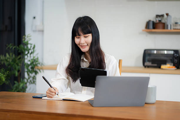 istock Lifestyle people, using computer working online, doing searching, sitting in the kitchen. Happy woman, entrepreneur, small business owner working online at home office. 2212703331