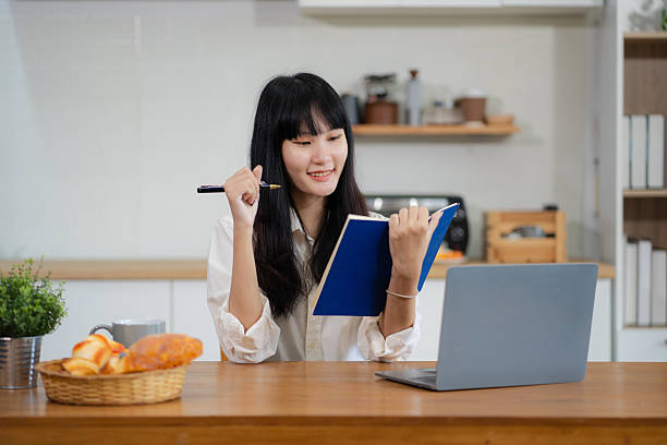 istock Lifestyle people, using computer working online, doing searching, sitting in the kitchen. Happy woman, entrepreneur, small business owner working online at home office. 2212703381