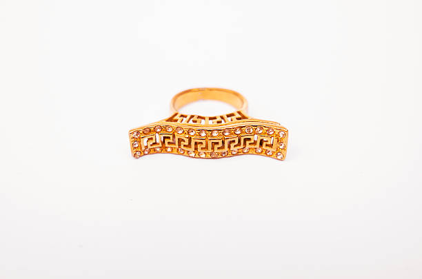 A luxurious golden ring with a bright gemstone, displayed on a white backdrop to enhance its shine and intricate details.