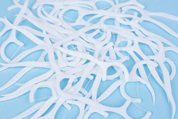 istock Dental floss picks on blue background. Soft floss picks. Dental picks. Plastic white dental toothpick with floss 2212704775
