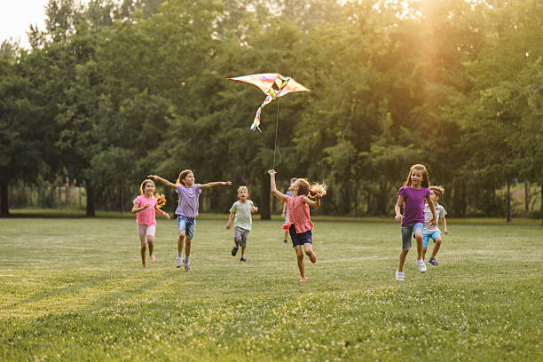 istock Children run with a kite during summer day in the park 2212705714