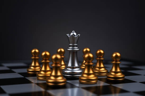 istock White chess queen surrounded by black pawns on chess board 2212706035