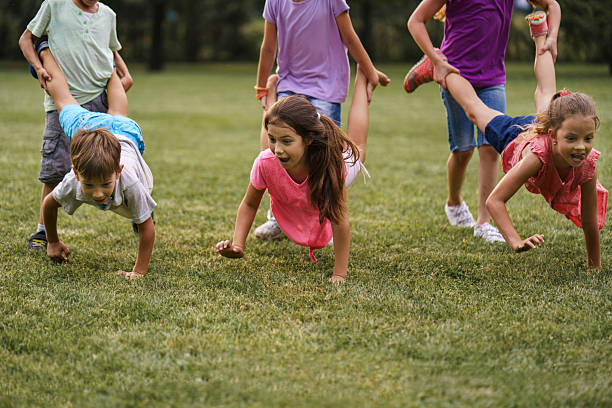 istock Children playing wheelbarrow race in public park 2212706256