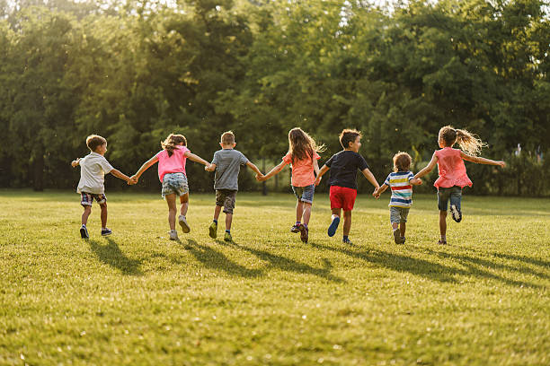 istock Boys and girls holding hands while running on a meadow 2212707211
