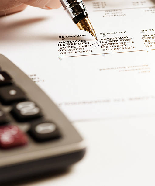 Extreme close-up of a person's hand checking financial figures on a printout of a spreadsheet.