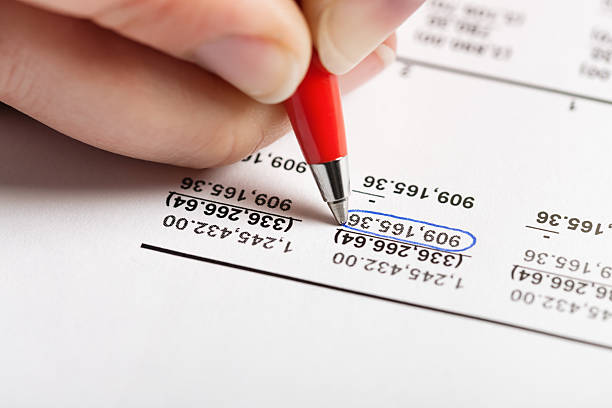 Extreme close-up of a person's hand checking financial figures on a printout of a spreadsheet.