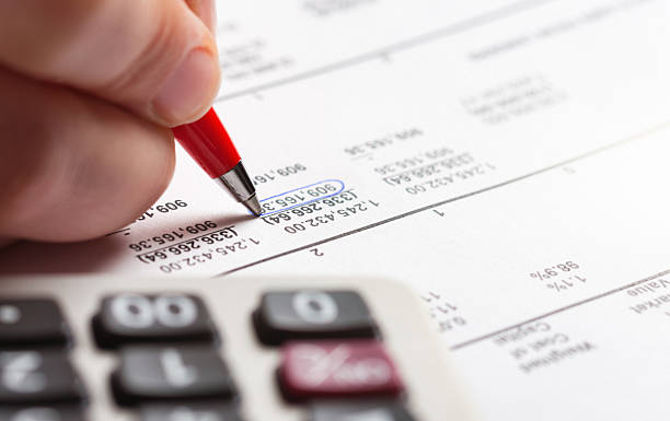 Extreme close-up of a person's hand checking financial figures on a printout of a spreadsheet.