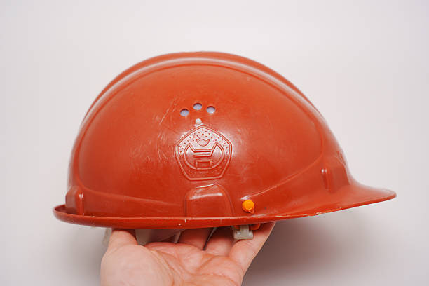 istock Construction helmet held in hand, showing bright orange color and design 2212710393