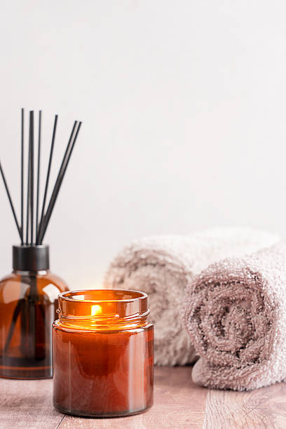 istock Cozy Spa Ambiance Candle, Diffuser in brown glass bottle and Rolled bath Towels 2212713642