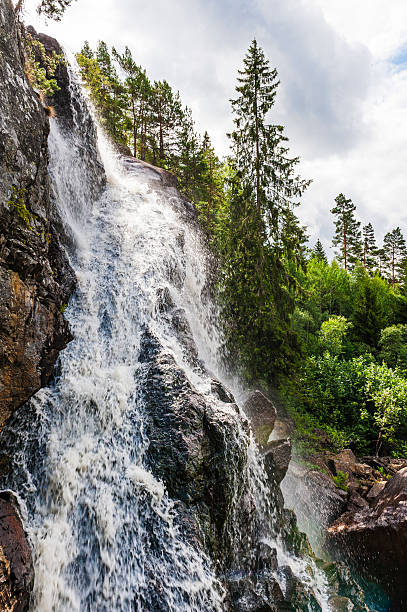 istock Sweden's stunning waterfall cascading down rocky cliffs surrounded by lush forest under a dramatic sky 2212716652