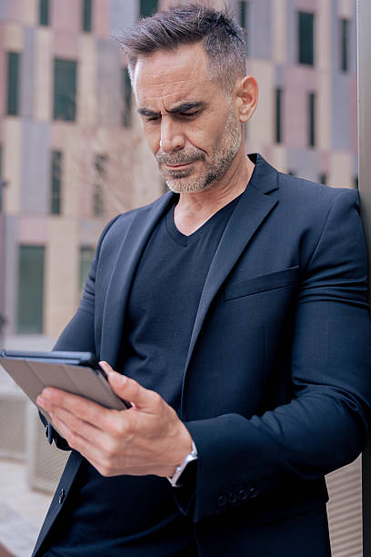 istock Mature businessman typing on tablet outdoors with modern building.Vertical 2212718185