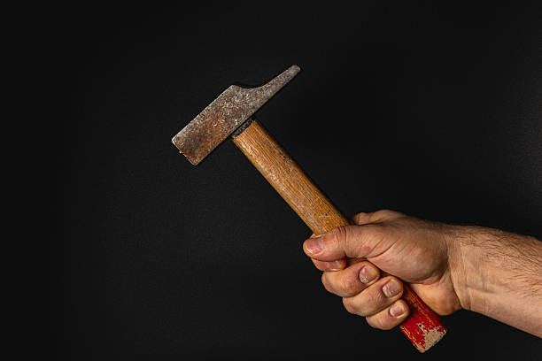 istock Hand holding a rusty hammer against a dark background 2212721840
