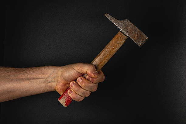 istock Hand holding a hammer against a dark background 2212722091