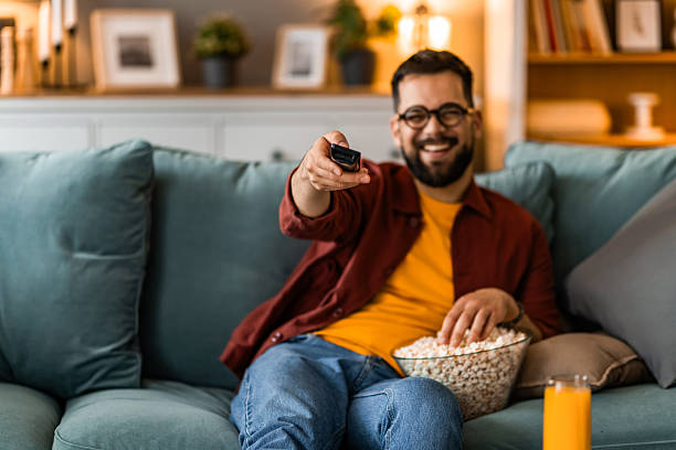 istock Young man relaxing at home and watching TV 2212726501