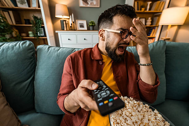 istock Scared man watching a horror movie on TV at home. 2212727033