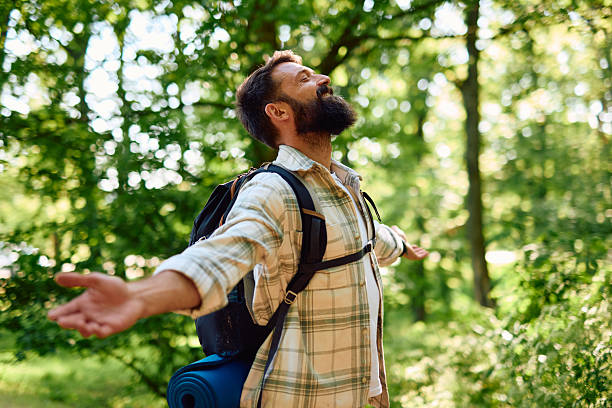 Hiker embracing nature with open arms in the forest