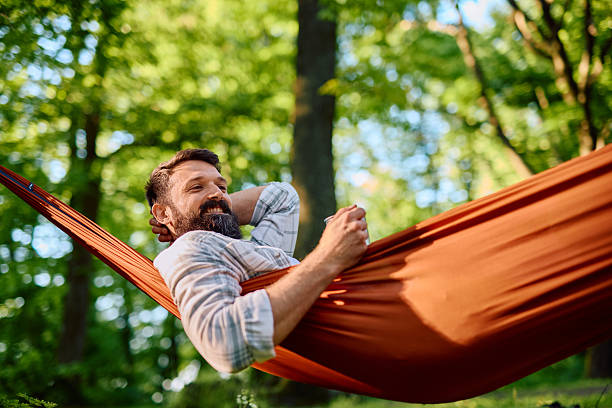 istock Man relaxing in hammock drinking coffee in forest 2212731932