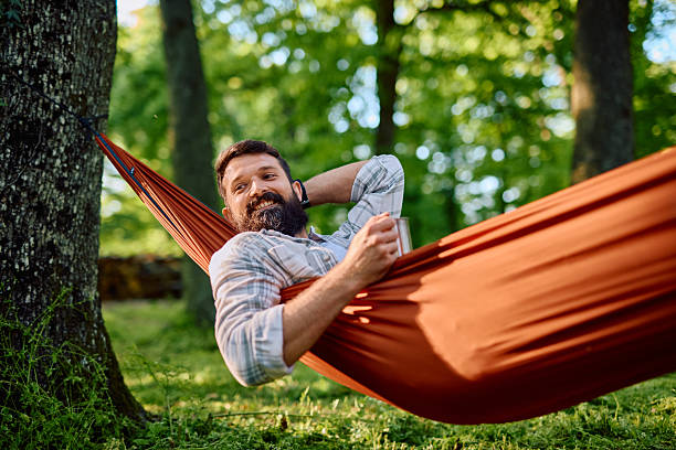 istock Man relaxing in hammock drinking coffee in forest 2212732088