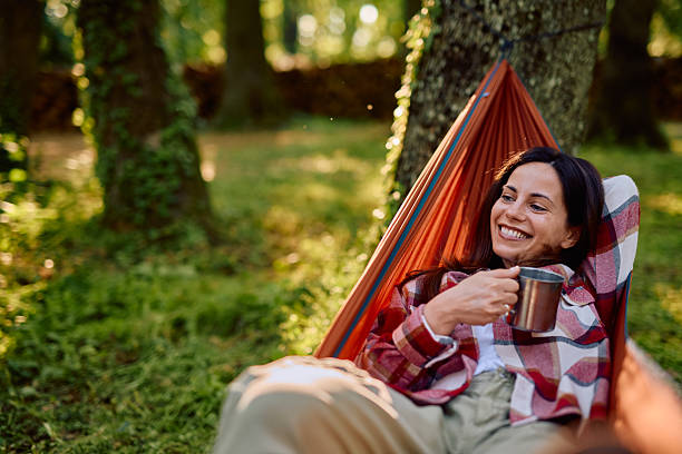 istock Happy camper relaxing in hammock drinking coffee in the forest 2212732329