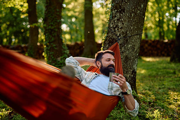 istock Bearded man relaxing in hammock enjoying a cup of coffee or tea 2212732386