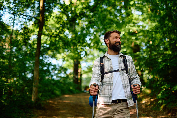 istock Happy hiker exploring nature walking in forest using trekking poles 2212733629