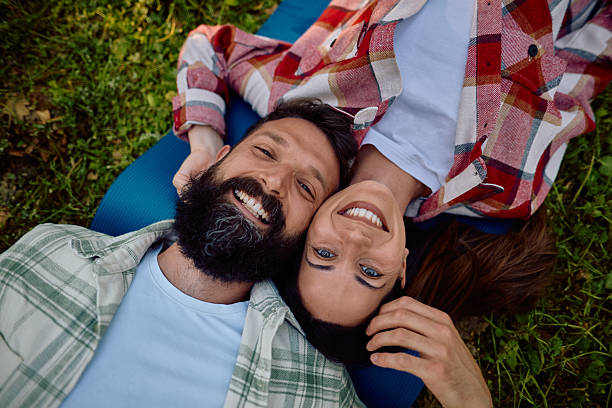 istock Happy couple lying on grass smiling at camera 2212734023