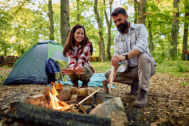 istock Couple camping and warming up by the bonfire in the forest 2212735336