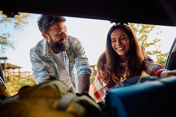 istock Happy couple loading luggage into car trunk, preparing for road trip adventure 2212735530