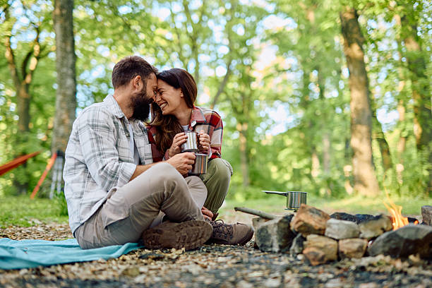istock Couple camping and drinking coffee near campfire in the forest 2212739906