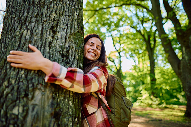 istock Happy hiker woman embracing a tree in the forest with closed eyes 2212739921