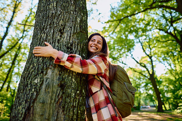 istock Happy hiker woman hugging a tree in the forest 2212740110