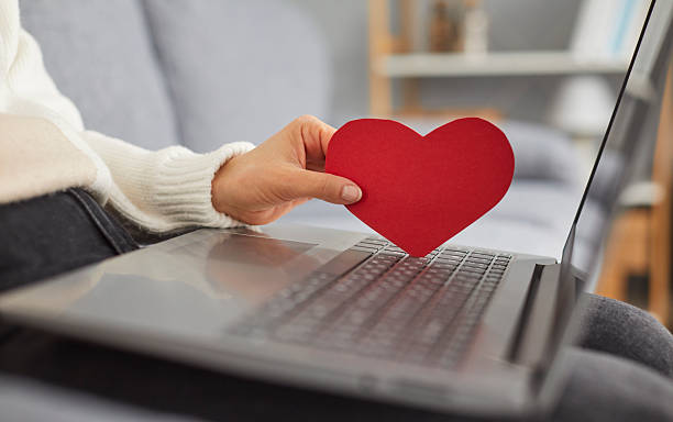 istock Young woman is using a laptop computer and looking for love on a dating web site 2212749392