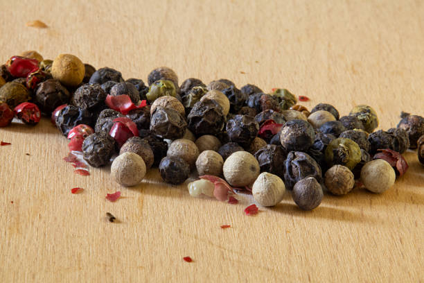 istock Mixed peppercorns scattered on a light wooden surface. 2212750347