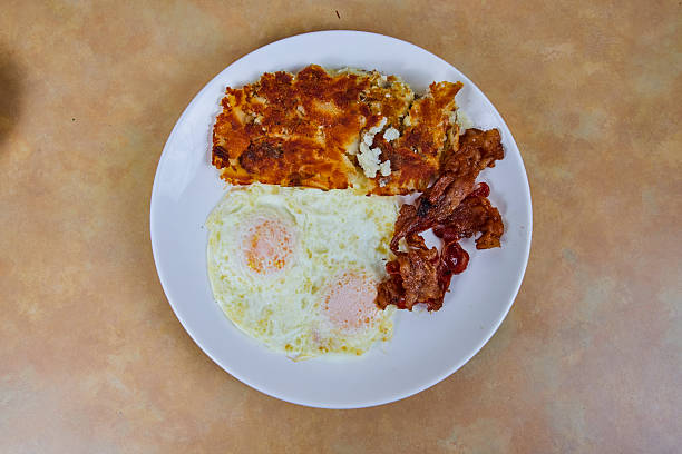 Hearty American breakfast of sunny-side-up eggs, crispy bacon, and golden hash browns served on a white plate, perfect for a comforting morning meal in Fort Wayne, Indiana.