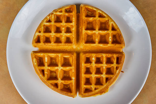 Golden morning delight! Freshly baked crisp waffle served on a white plate, perfect for breakfast menus and culinary masterpieces.