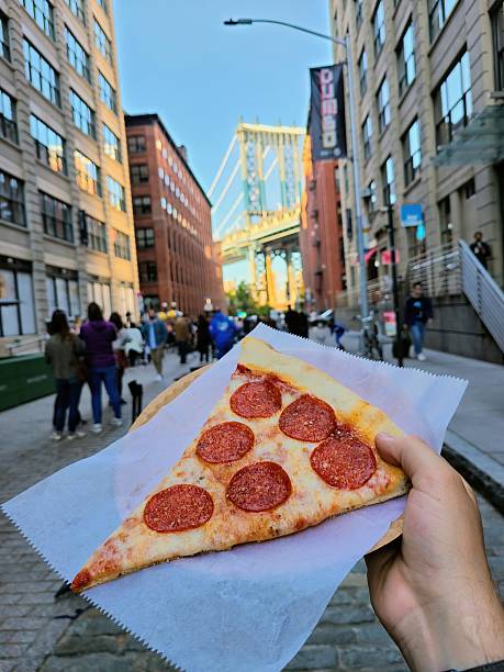 Hand-Held Pepperoni Pizza with DUMBO Bridge Background