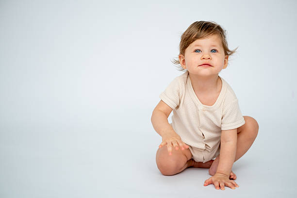 istock A baby boy crawls on a white isolated background with a place for text in light clothes. A small happy child, space for text 2212756926
