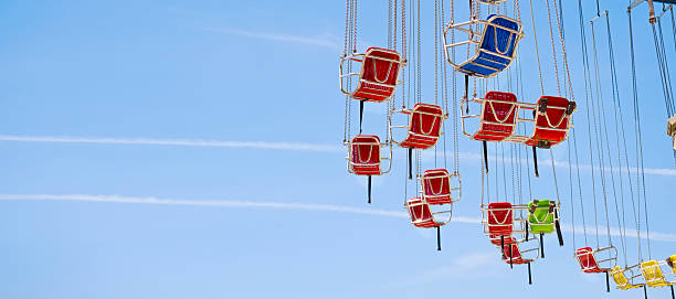 Teenagers sitting on chain carousel or chair swing ride. The kids are enjoying the ride at the travelling carnival.Canon R5