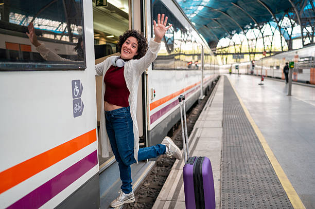 istock Happy tourist waving goodbye while leaving train at station 2212766128