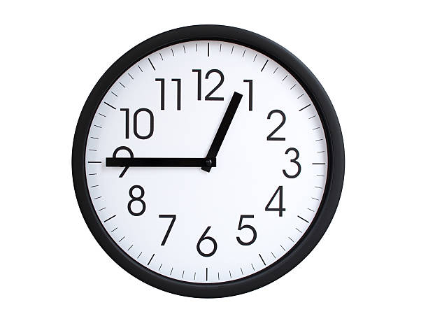 A modern white face with black numbers analog wall clock Showing 00:45 or 12:45. Isolated on White Background.