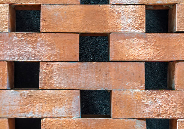 A brick wall with black and white squares in it. The wall is made of red bricks